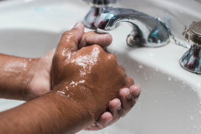 A person washing their hands with soap and water, emphasizing cleanliness for tattoo aftercare