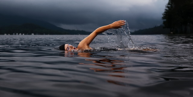 A tattooed man swimming in the river, indicating swimming is not allowed.